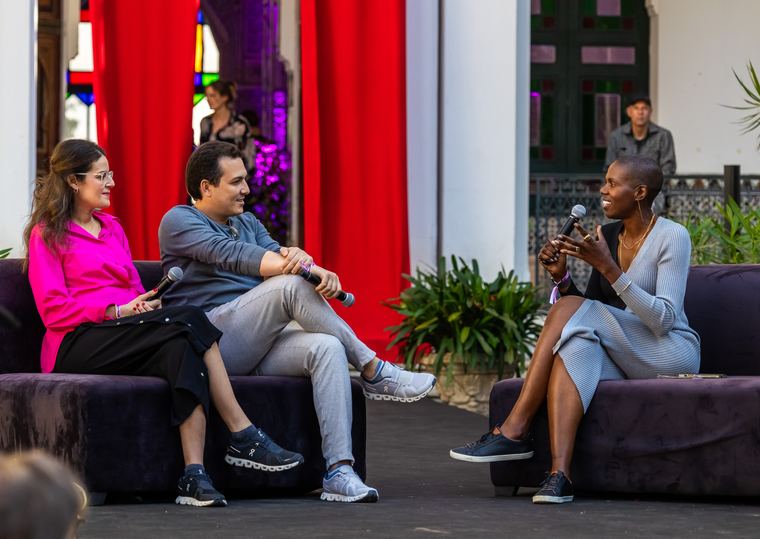 Francesca Hogi moderating a conversation between two speakers